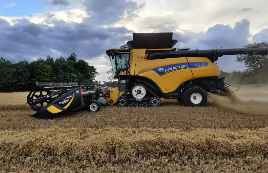 New Holland CR10.90 combine cutting a field at dusk