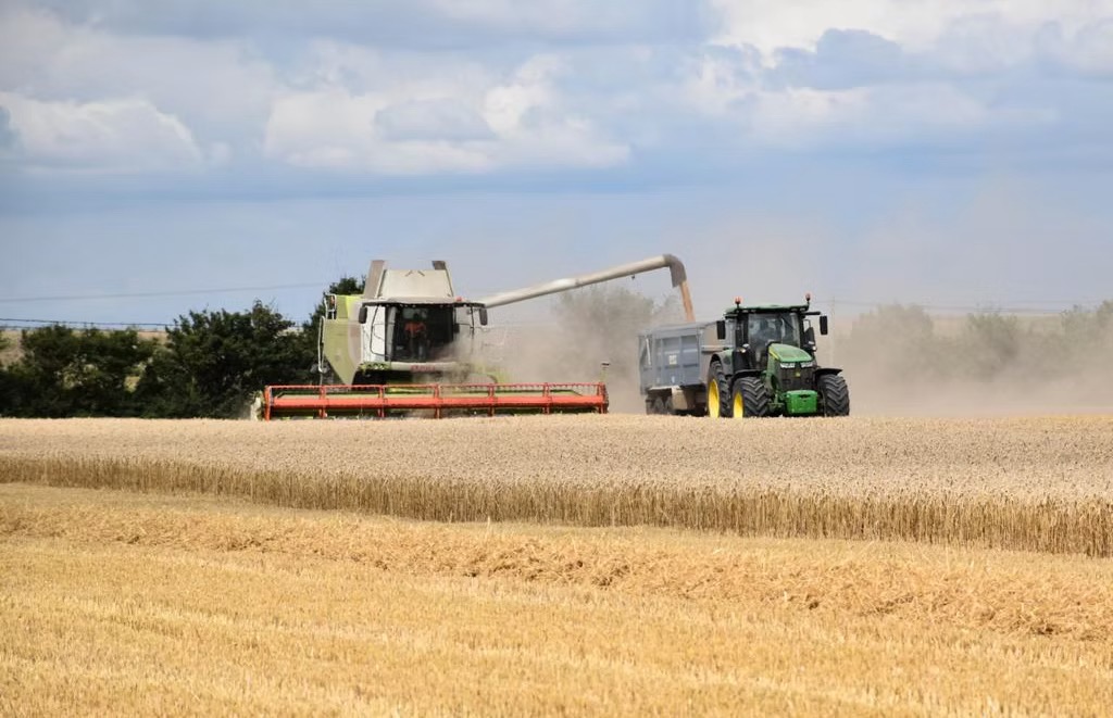CLAAS combine and John Deere tractor working together in a field